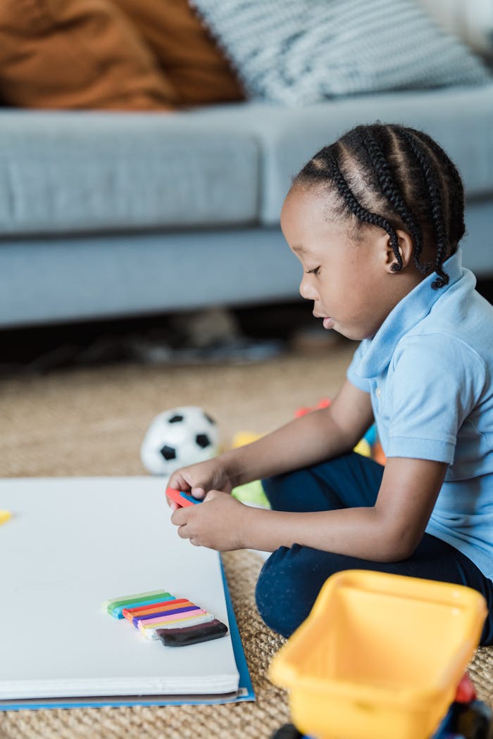 Crafting Captivating Headlines: Your awesome post title goes here African American child playing with colorful plasticine on floor indoors, promoting creativity.
